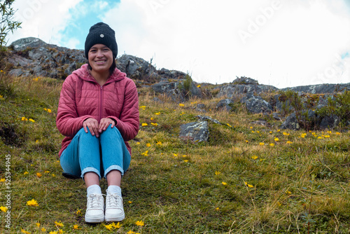 
Atractiva mujer sentada en el césped después de una caminata y disfrutando de la hermosa naturaleza photo