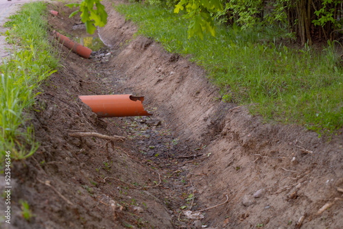 sewer pipes sticking out of the ground above a trench dug for sewage drains rainwater drains photo taken in summer in warm weather during the day