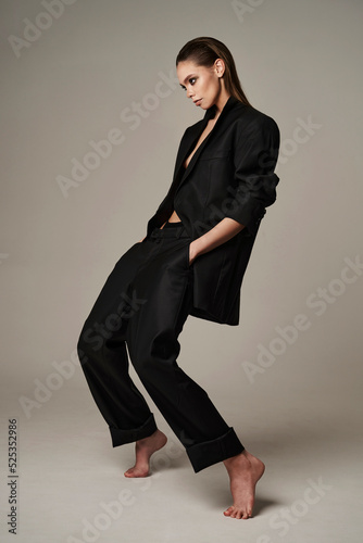 Fashion portrait of a beautiful young woman posing in a black evening suit
