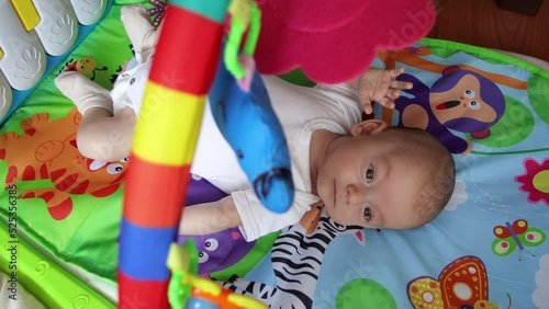 Newborn baby playing on the baby gym playmat