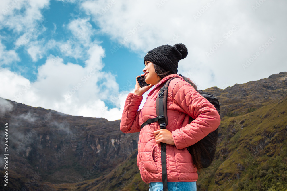 Mujer de pie contra las montañas y hablando por teléfono