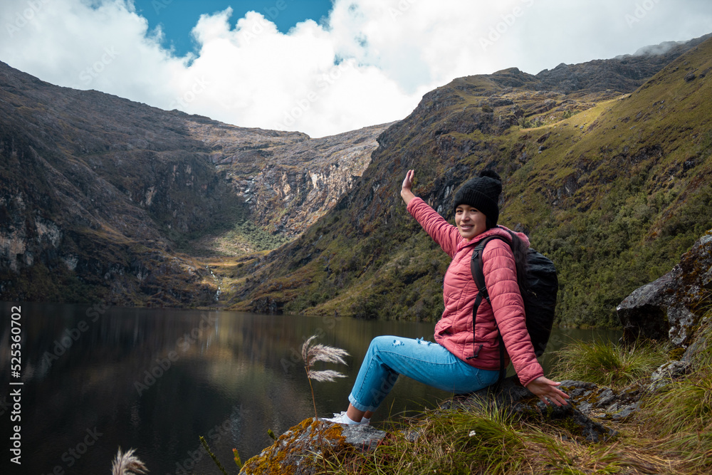 Naklejka premium Mujer alegre posando contra un lago rodeado de montañas