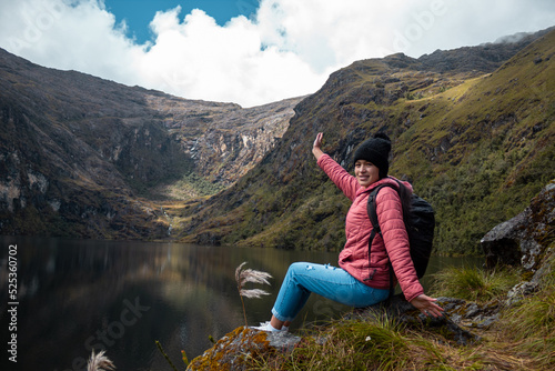Mujer alegre posando contra un lago rodeado de montañas © Yoel Garay