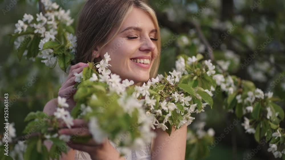 joyful young woman is smiling and playing with blooming branches of cherry tree, portrait joyful young woman is smiling and playing with blooming branches of cherry tree, portrait