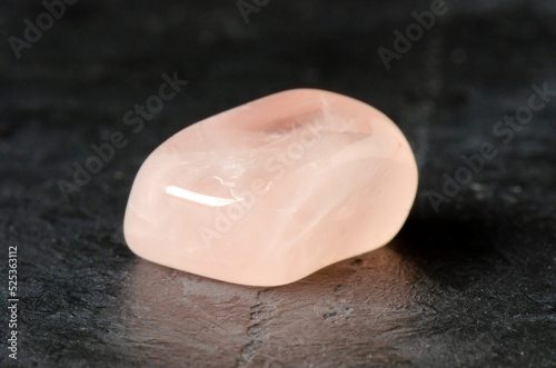 The mineral rose quartz on a black concrete background. The concept of using minerals and crystals in astrology and alternative or complementary medicine.