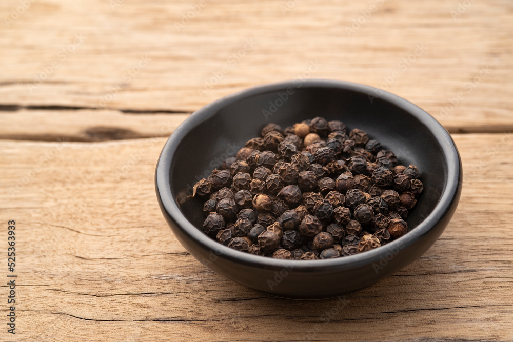 fragrant spices ,black peppercorn in black bowl on wood table
