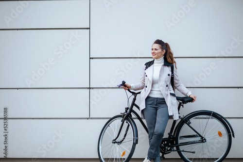 smiling stylish female with bicycle outside on city street