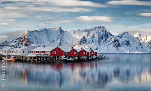 Wonderful winter view on snowcapped mountains, red fishing huts and cloudy sky. Typical nature landscape of Lofoten islands. Norway. Travel, adventure and freedom concept. popular travel destinations