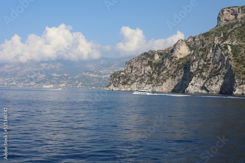 Rocky coast of the island. Scenic Amalfi Coast view from the sea. Beautiful seascape with yacht near shore in sea. Modern sailboat on a sunny summer day. Sailing near coastline in Mediterranean Sea.