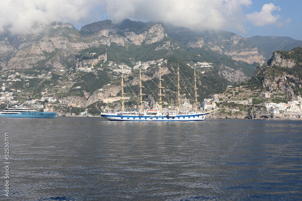 Frigate ship in the harbor. Beautiful seascape with yacht near shore in the sea. Modern sailboat on a sunny summer day.  Sailing near mountain coastline in  Mediterranean Sea. Scenic Amalfi Coast view