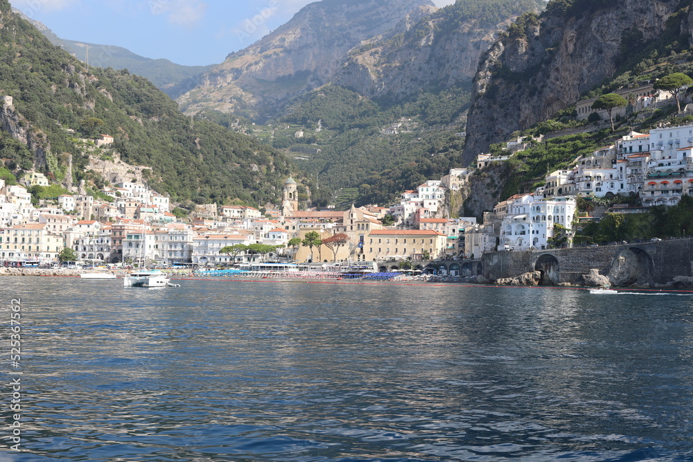 Scenic Amalfi Coast view. Beautiful seascape with yacht near shore in the sea. Modern sailboat on a sunny summer day. Sailing near coastline in the Mediterranean Sea.