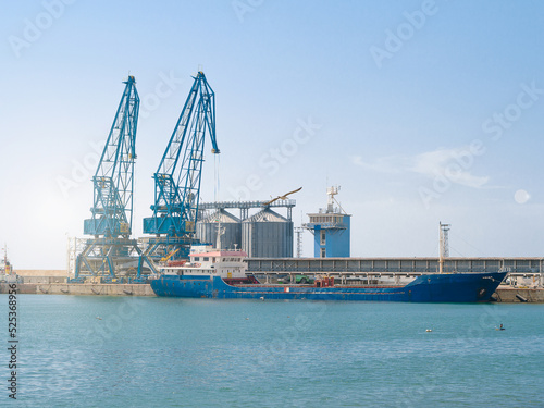 food crisis 2022. Unloading grain of sea dry cargo vessel through an automatic line in seaport from silos of grain storage. Bunkering of dry cargo ship with grain