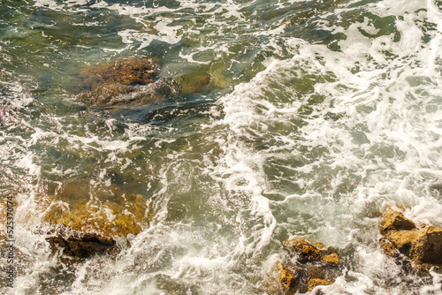 Sea waves breaking on rocks and hitting the shore.