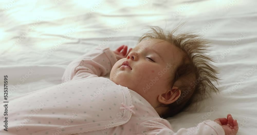 Close up view beautiful serene newborn baby girl relaxing, falling asleep in bed, looks serene and carefree. Healthy day-time nap, enough sleep and rest for children growth, babyhood, infancy concept Close up view beautiful serene newborn baby girl relaxing, falling asleep in bed, looks serene and carefree. Healthy day-time nap, enough sleep and rest for children growth, babyhood, infancy concept
