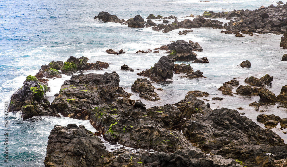 rocas de lava cubiertas de musgo en el mar atlántico de las costas de Tenerife en las Islas Canarias con el oceano cocando con ellas .