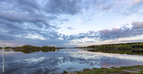 Fototapeta Naklejka Na Ścianę i Meble -  Evening landscape, sunset on the river. Wide river, horizon, clouds are reflected in the water.