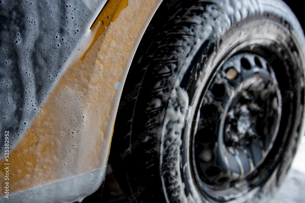 Modern washing with foam and high-pressure water of a white car. Foam on the car. Modern washing with foam and high-pressure water of a white car. Foam on the car.