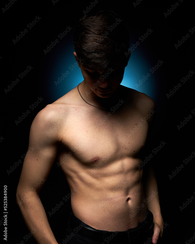 a healthy athletic teenager shows off his body against a dark background, the concept of proper nutrition