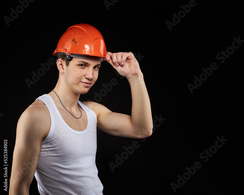 Young construction worker is a teenager in a hard hat and a white T-shirt