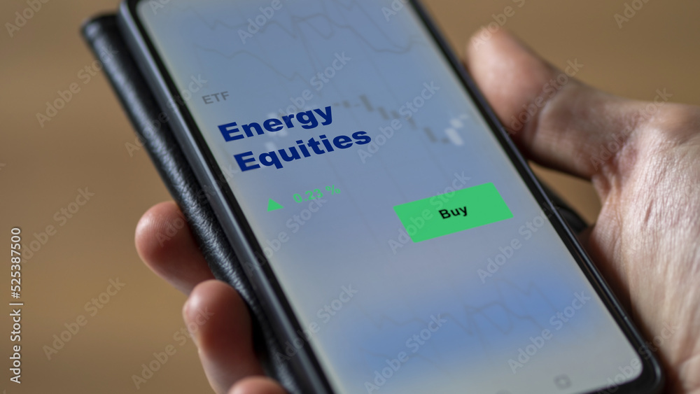 An investor's analyzing the energy equities etf fund on screen. A phone shows the ETF's prices energy equity to invest An investor's analyzing the energy equities etf fund on screen. A phone shows the ETF's prices energy equity to invest