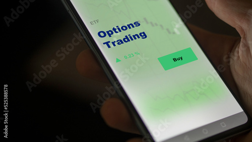 An investor's analyzing the option trading etf fund on screen. A phone shows the ETF's prices stocks to invest