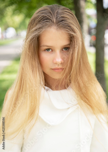 portrait of a little  beautiful  girl with long blond hair in the green park on sunny spring day