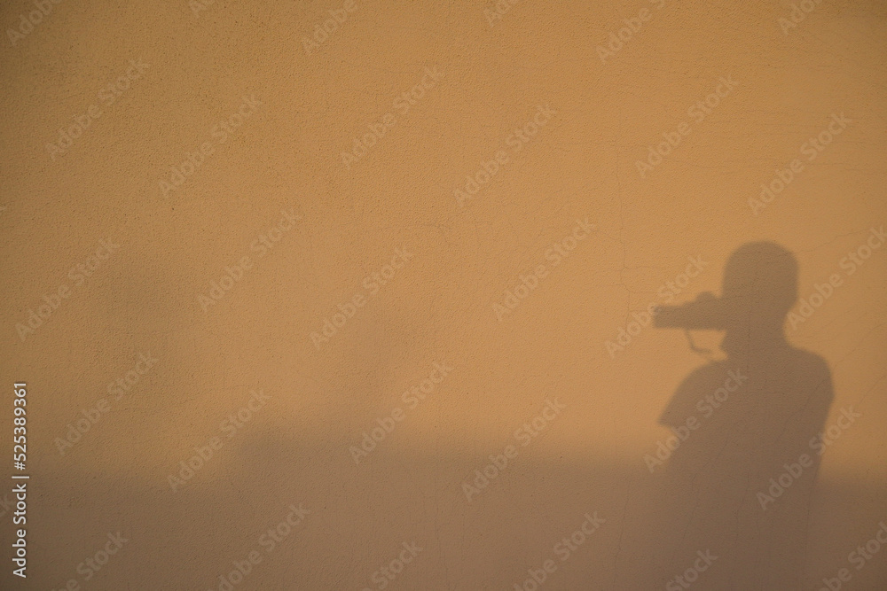 Shadows in a wall. Reflection / silhouette of the photographer taking photo of himself. Silhouette of photographer taking a photo
