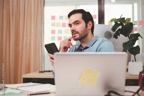 Portrait of smiling businessman with laptop sitting at desk in office. Cheerful casual caucasian employee, Handsome businessman using mobile phone. successful business working at office. mobile phone.