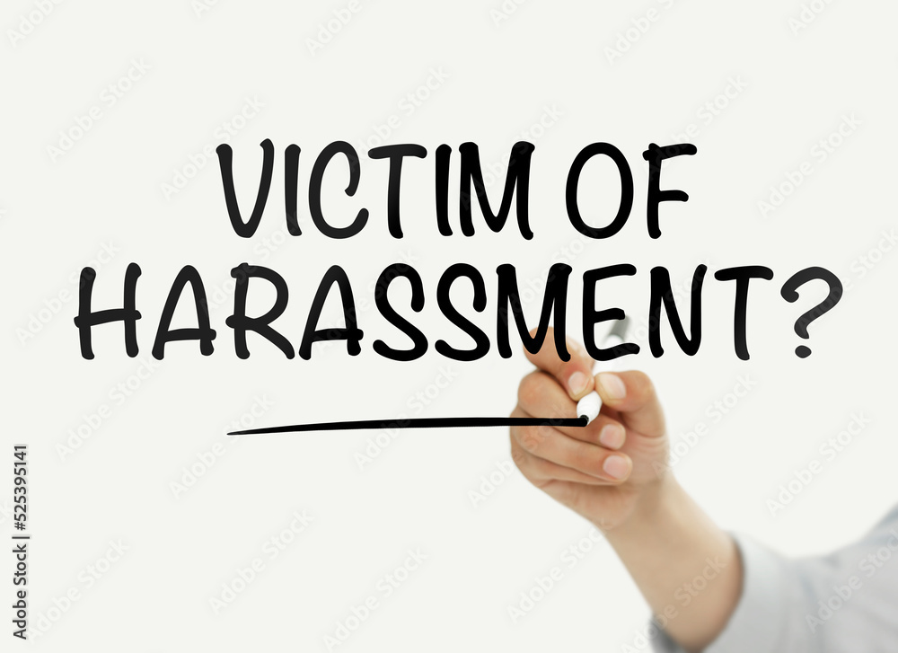 Man writing “Victim of harassment?” text on a transparent wipe board Man writing “Victim of harassment?” text on a transparent wipe board