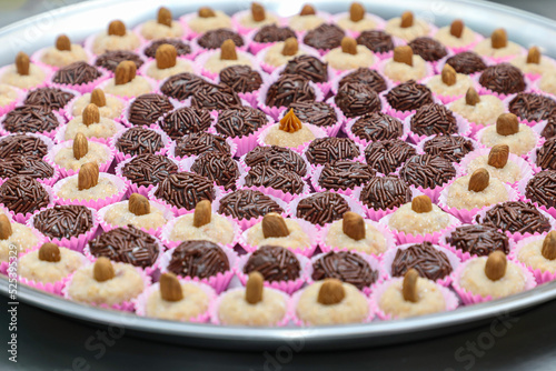 Tray with brigadiers and cashews divided in a circular shape in a shape, in the center a different sweet with dulce de leche on top. photo