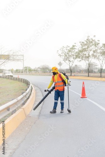 Latin american man cleaning the road with a leaf blower. Copy space.