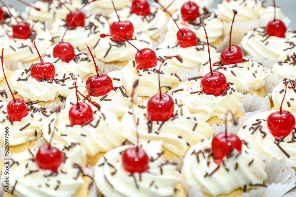 Various mini cakes with whipped cream, chocolate sprinkles and cherries on top, as the focus on these. Various mini cakes with whipped cream, chocolate sprinkles and cherries on top, as the focus on these.