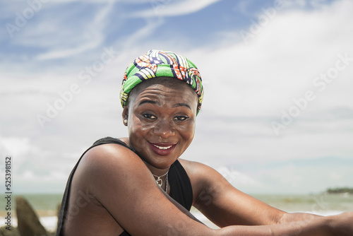 Happy Africa Woman with headdress from Ghana on a beach on the coast of Axim Ghana West Africa photo