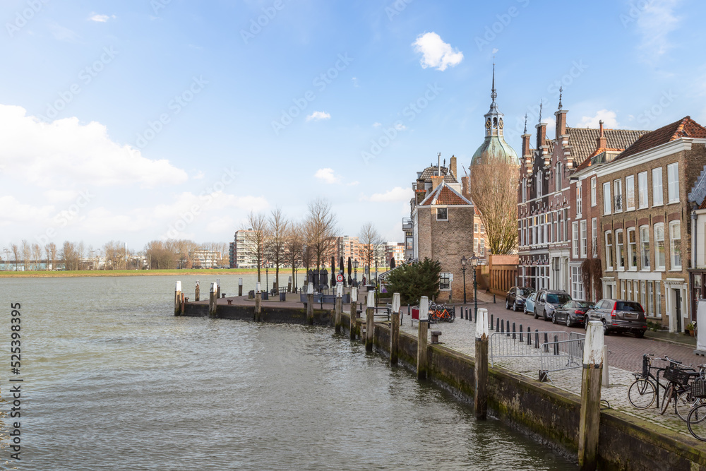 Obraz premium Canal houses with the dome of the medieval city gate on the quay in the background, in the old part of the historic city of Dordrecht.