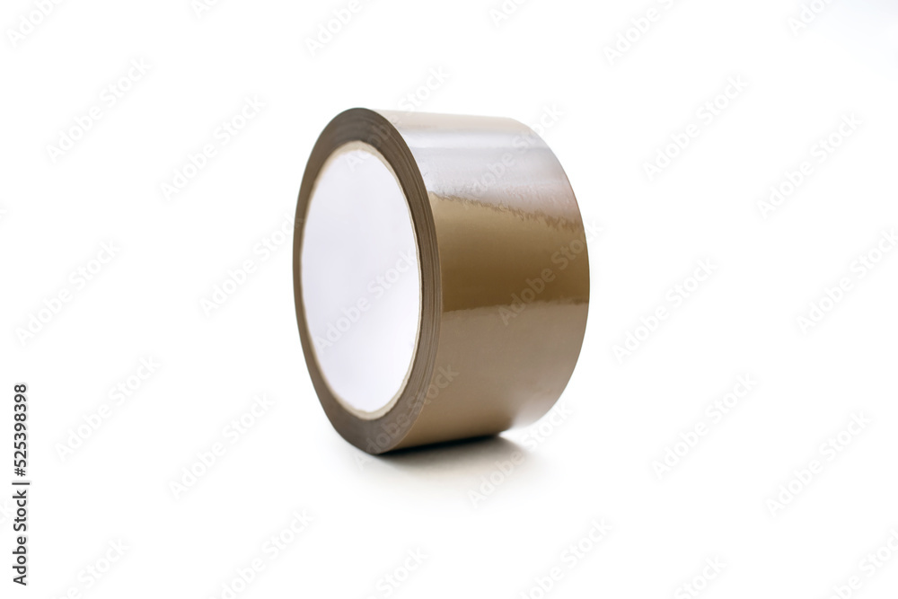 A roll of brown adhesive tape on a white background in the center of the image. A stationery item in the form of sticky tape for gluing paper or for a delivery service A roll of brown adhesive tape on a white background in the center of the image. A stationery item in the form of sticky tape for gluing paper or for a delivery service