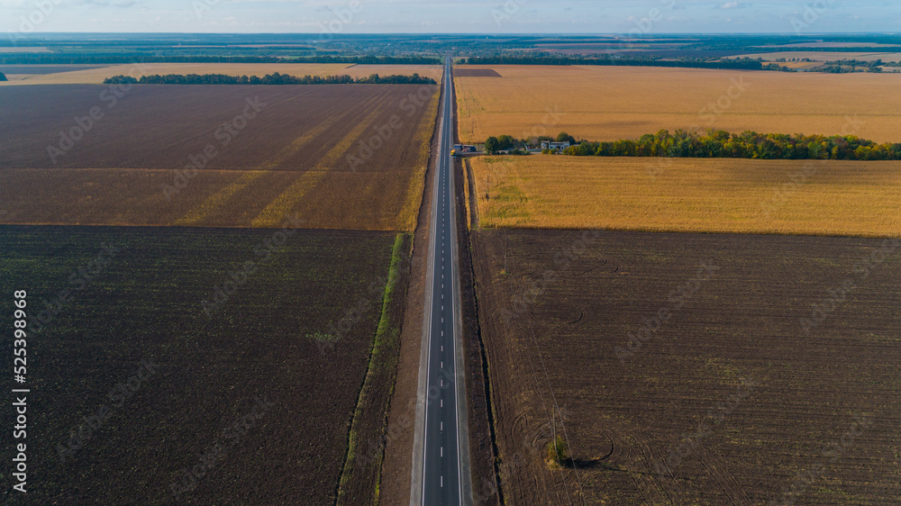 Fototapeta premium Aerial view beautiful summer nature landscape on a sunny day. Drone shot new road between a field. Blue sky