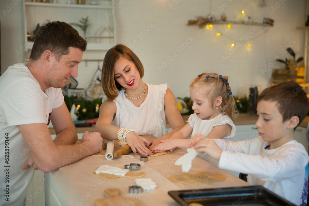 Obraz premium happy family dad, mom and two kids make Christmas cookies and have fun together at home in the kitchen. Children siblings making homemade xmas gingerbreads