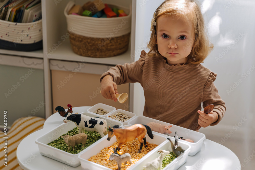 A Little Girl Playing With Farm Animals In Sensory Bin In Nursery