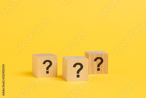 front view on wood cubes with question marks. many question arising concept, yellow background