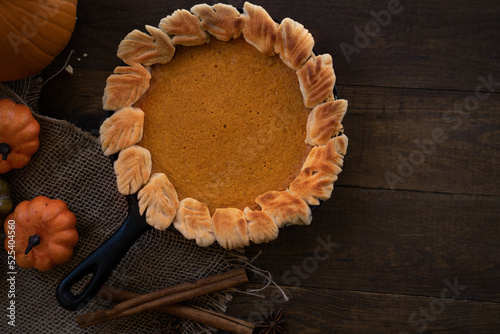 Homemade pumpkin pie baked in cast iron pan, on wooden background photo