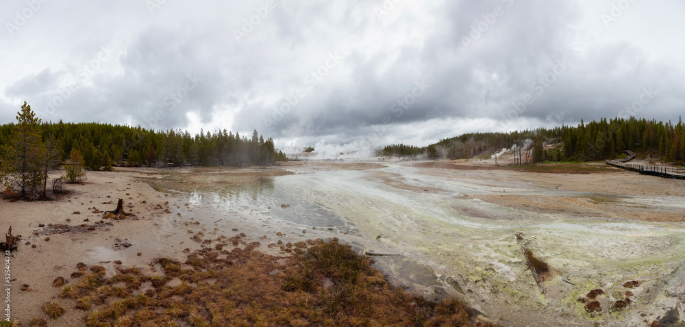 Hot spring Geyser with colorful water in American Landscape. Cloudy Sky. Yellowstone National Park, Wyoming, United States. Nature Background Panorama Hot spring Geyser with colorful water in American Landscape. Cloudy Sky. Yellowstone National Park, Wyoming, United States. Nature Background Panorama