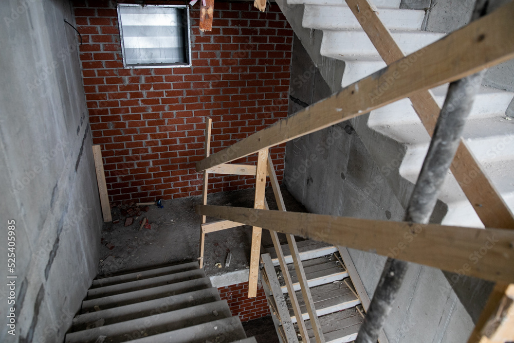 Obraz premium Scaffold and temporary access stairs erected on new housing development construction site around new multi-storey house to allow cladding, windows and roof installation