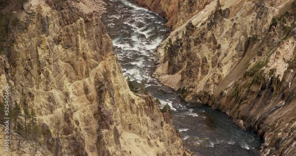 A large river cuts through mountains below a massive waterfall in Yellowstone National Park A large river cuts through mountains below a massive waterfall in Yellowstone National Park