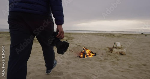 Man walks past bonfire with camera at Oceano Dunes SVRA at Pismo Beach, California photo
