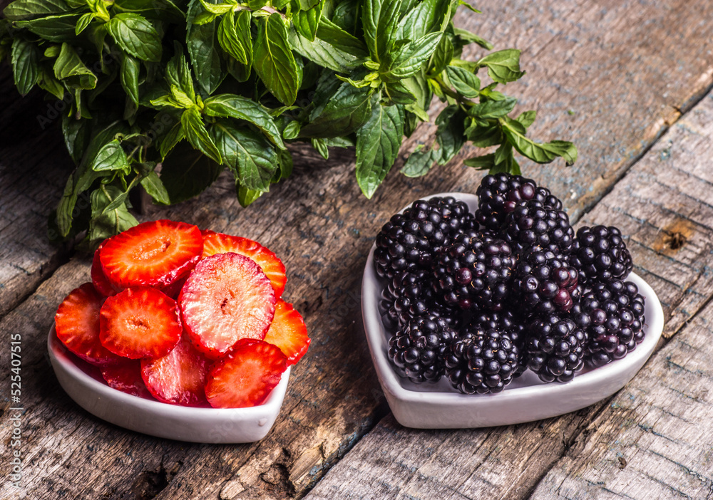 A bowl of strawberries and blackberries on a wooden background.