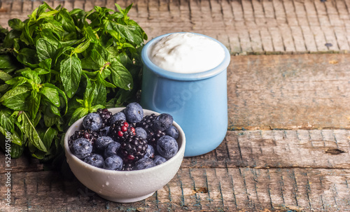A jar of homemade yogurt and a bowl of berries. Blueberries and yogurt