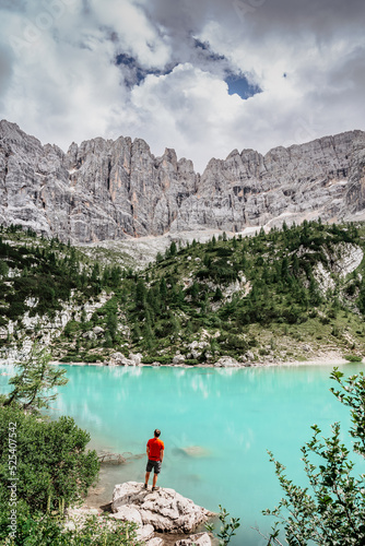 Male backpacker enjoying turquoise Lago di Sorapiss mountain lake,Dolomites Mountains,Italy.Active people in nature.Limestone peaks,canyons,crystal clear water,hiker.Adventure freedom concept.