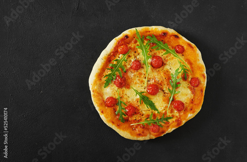 Traditional Italian pizza with tomatoes and rugula on the dark background - homemade. Copy space.