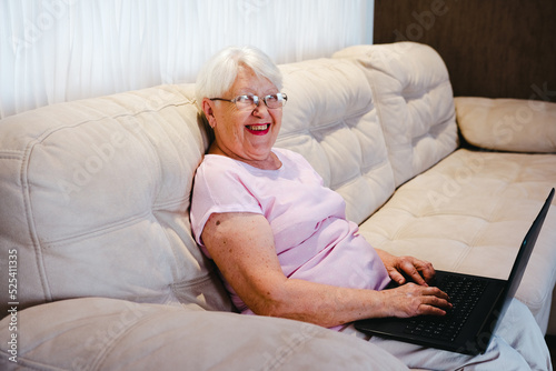 happy elderly woman using laptop computer at home. Senior mature older woman watching business training, online webinar on laptop computer remote working or social distance learning from home. 60s