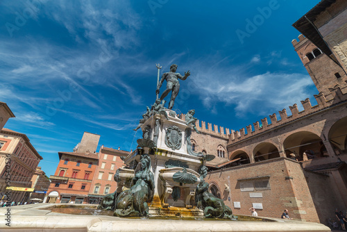 Bologna, Italy - August 21, 2022: street view of the Fondana di Nettuno in Bologna, people are visible in the far distance under a blue sky of summer. photo